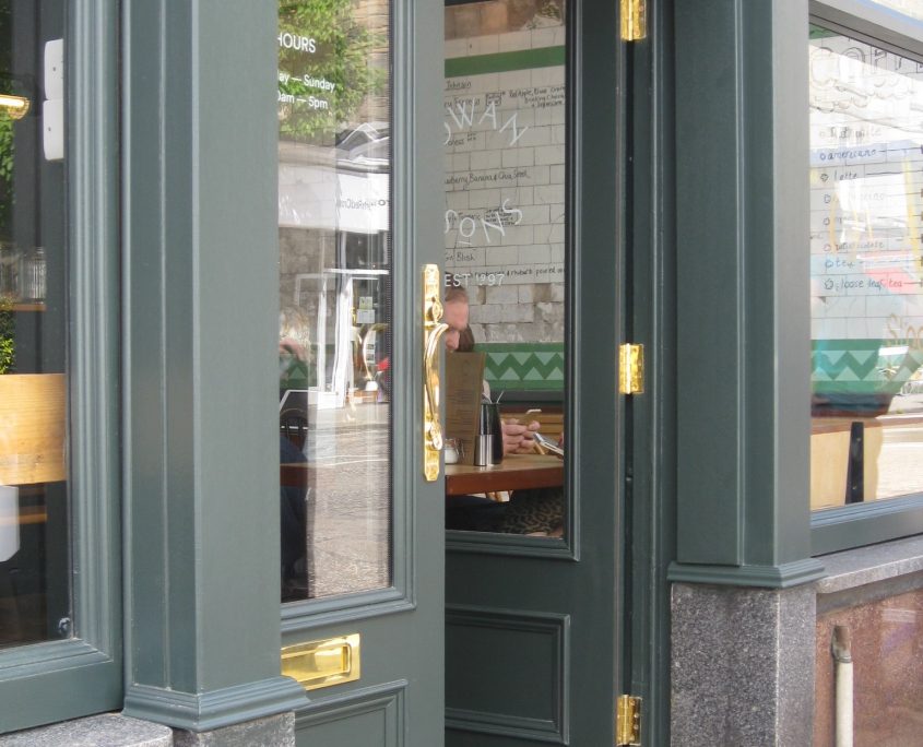 earthy green shop front door with high polished gold door fixings