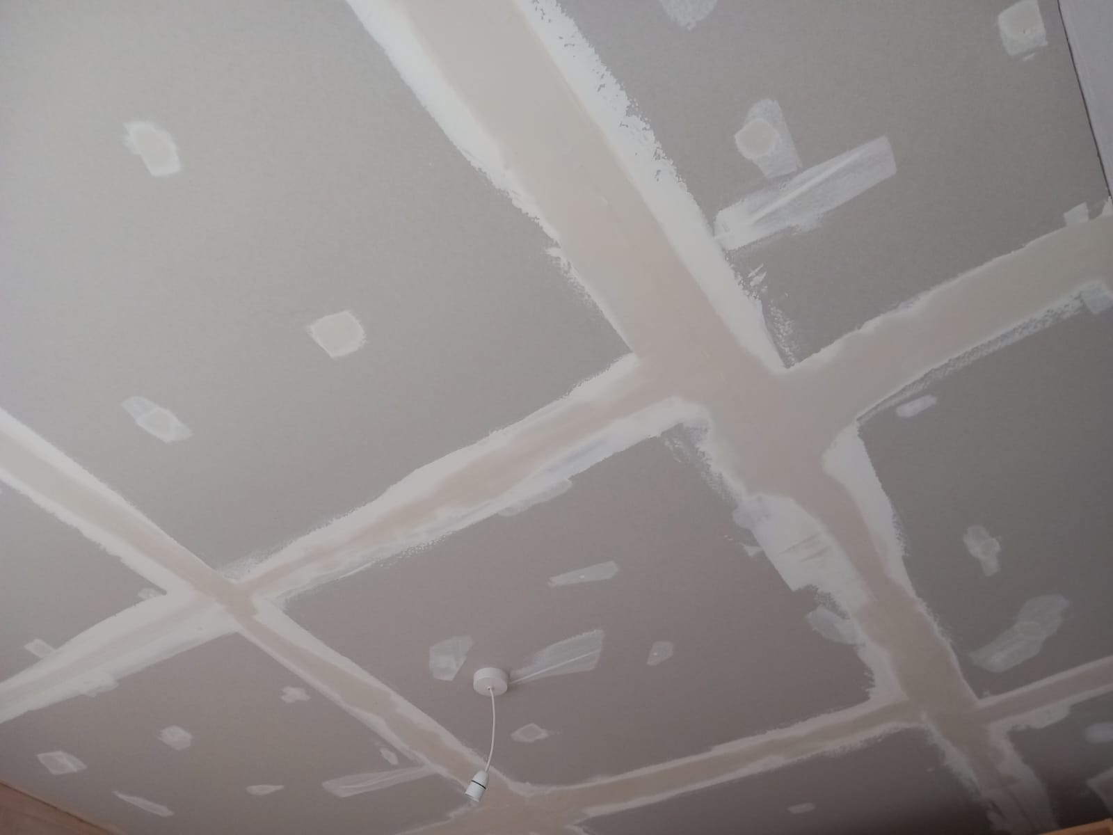 Large plasterboard ceiling with filled joints and a small lighting pendant.